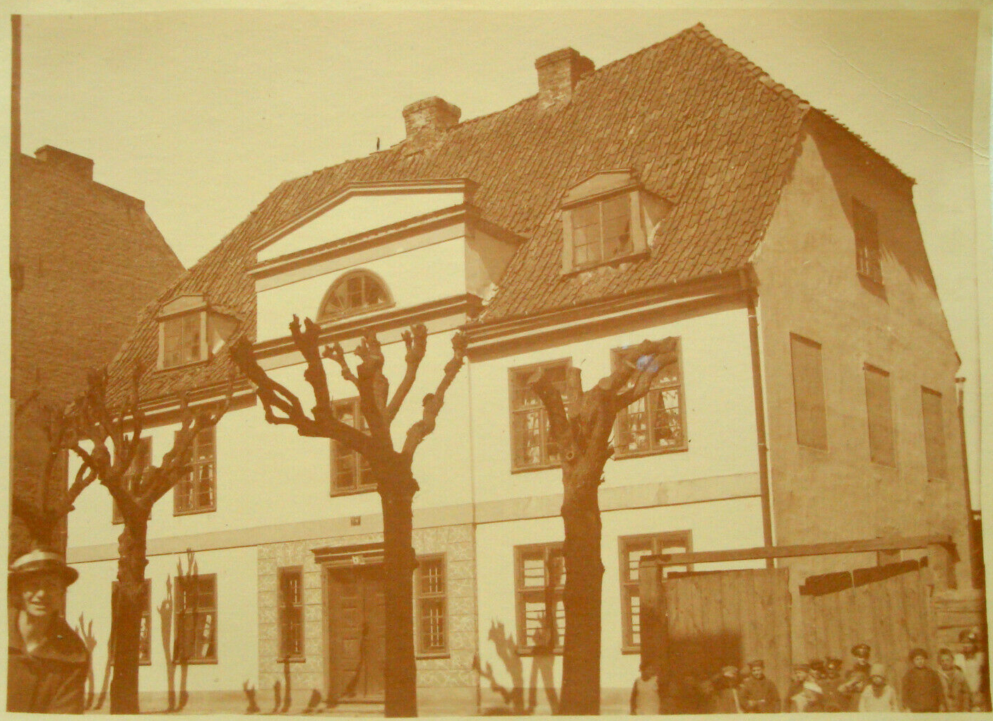 Na starym zdjęciu widać piętrowy budynek mieszkalny o białej fasadzie i spadzistym dachu